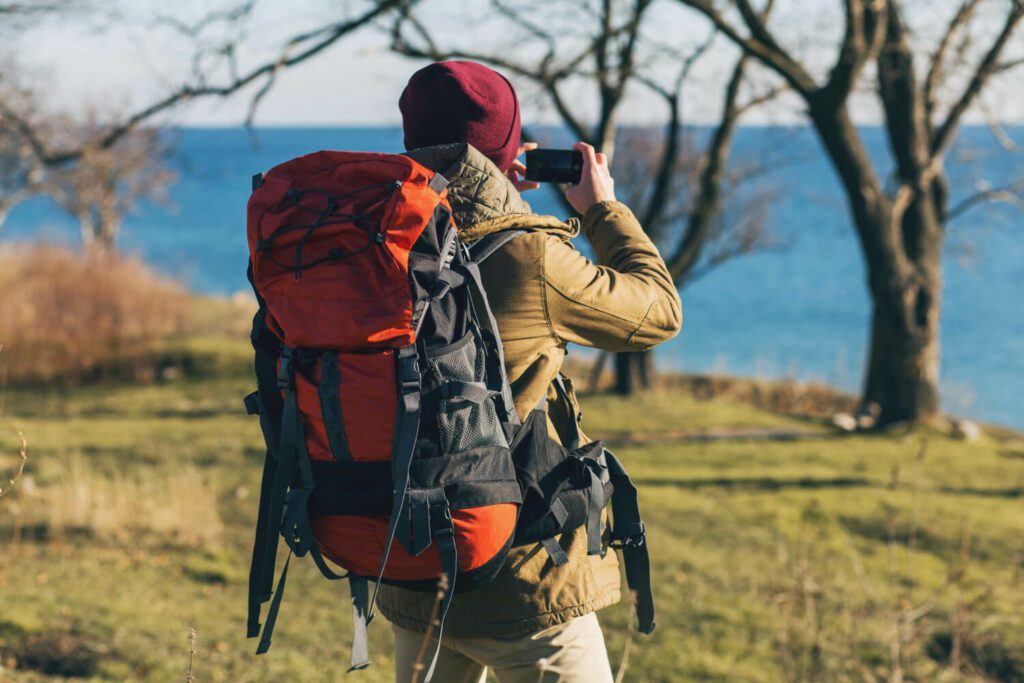 Homme équipé d'un sac de randonnée qui prend une photo d'un lac