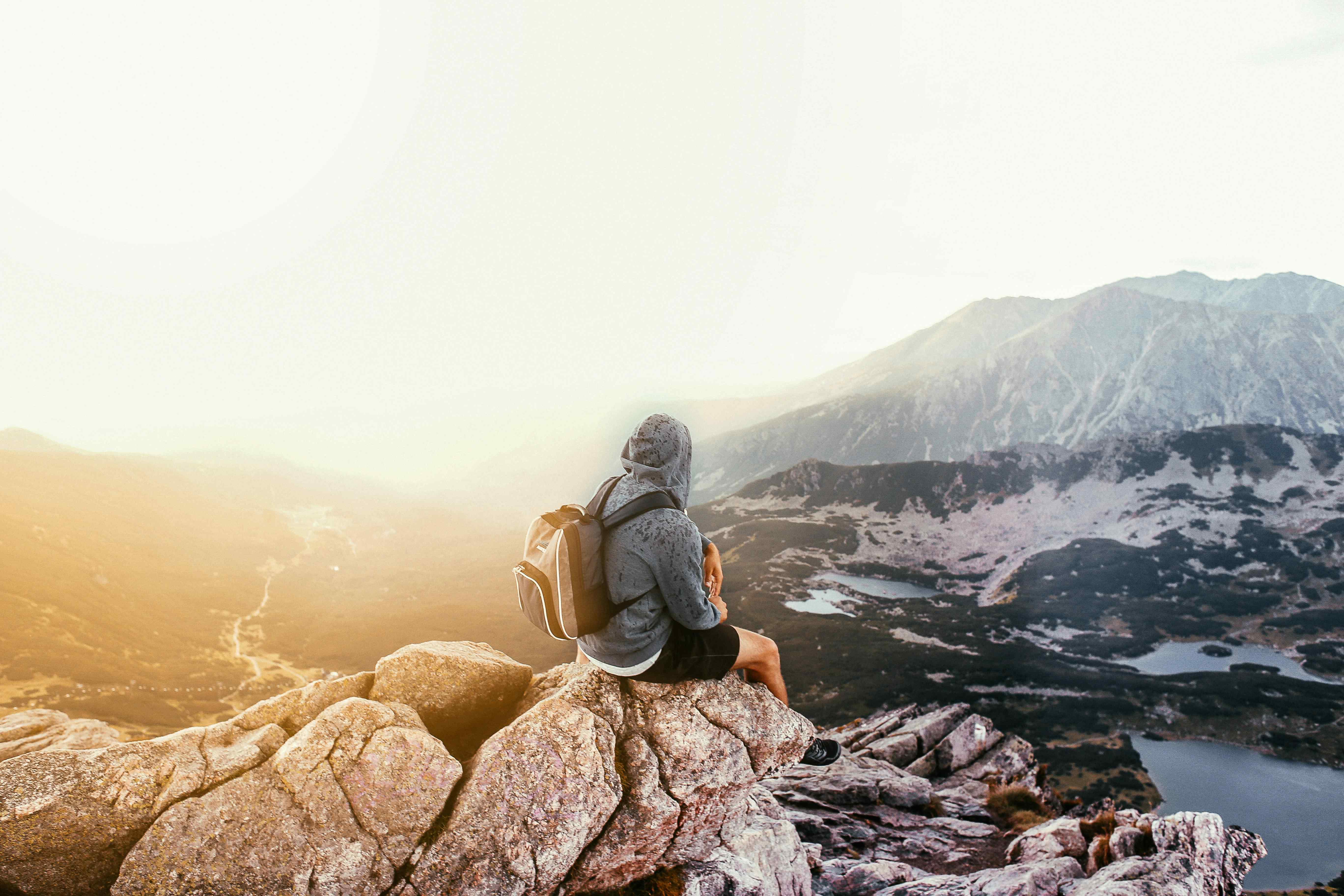 Un homme assis sur un rocher en haut d'une montagne